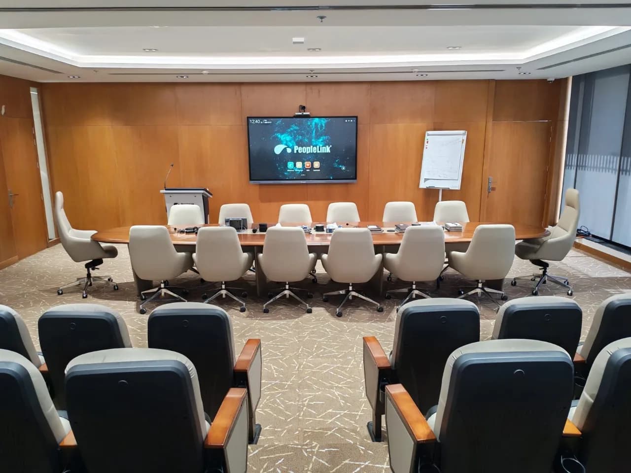 Training auditorium with tiered seating facing a PeopleLink interactive display