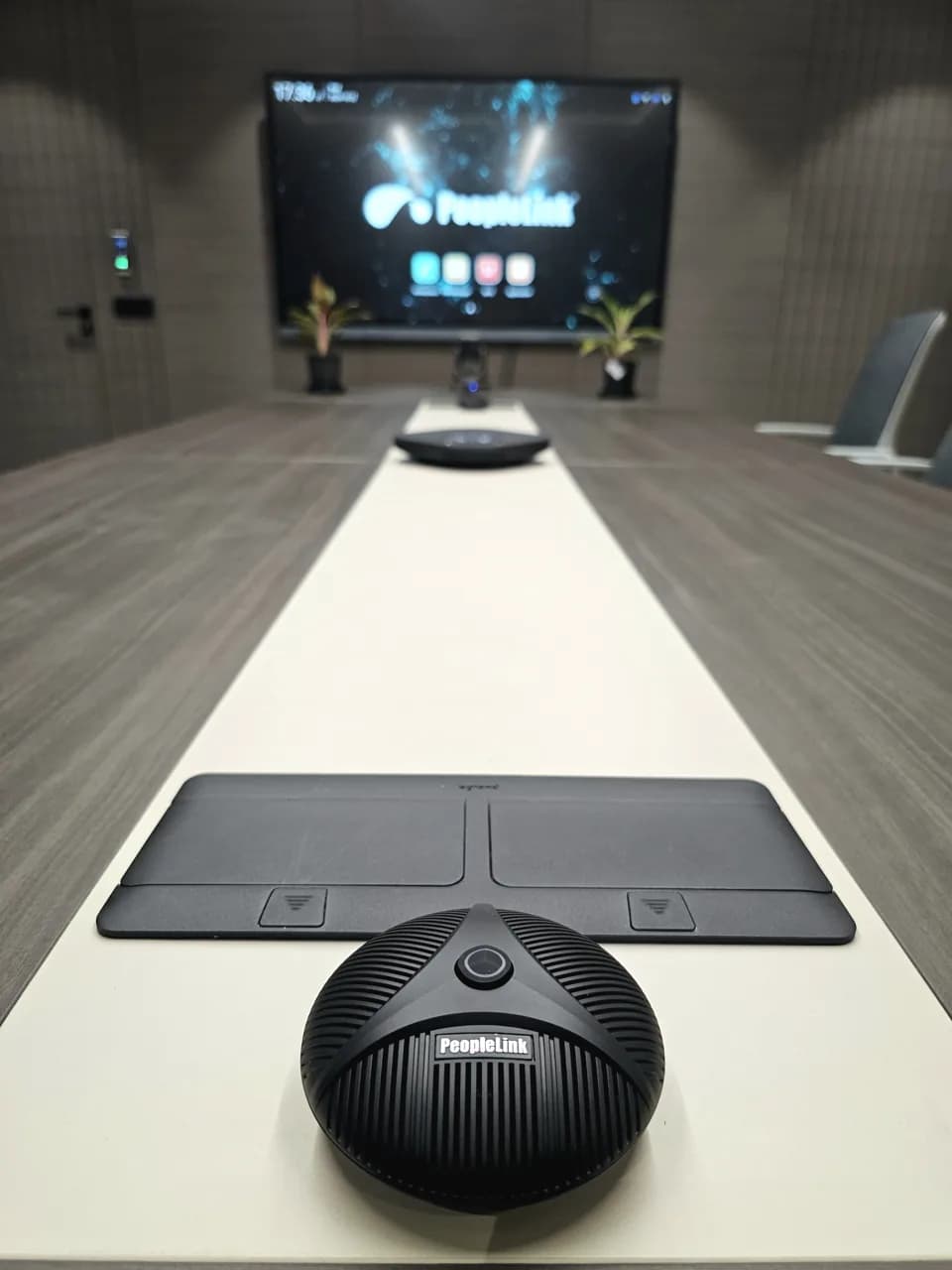 Boardroom table with a boundary microphone and a branded PeopleLink display
