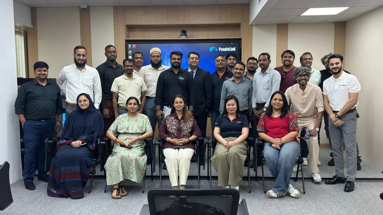 Group of channel partners in front of a PeopleLink display after a training session