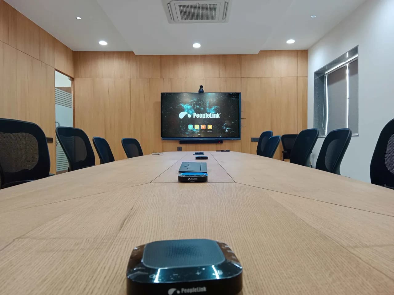 Boardroom with speakerphones in the foreground and an interactive display with camera