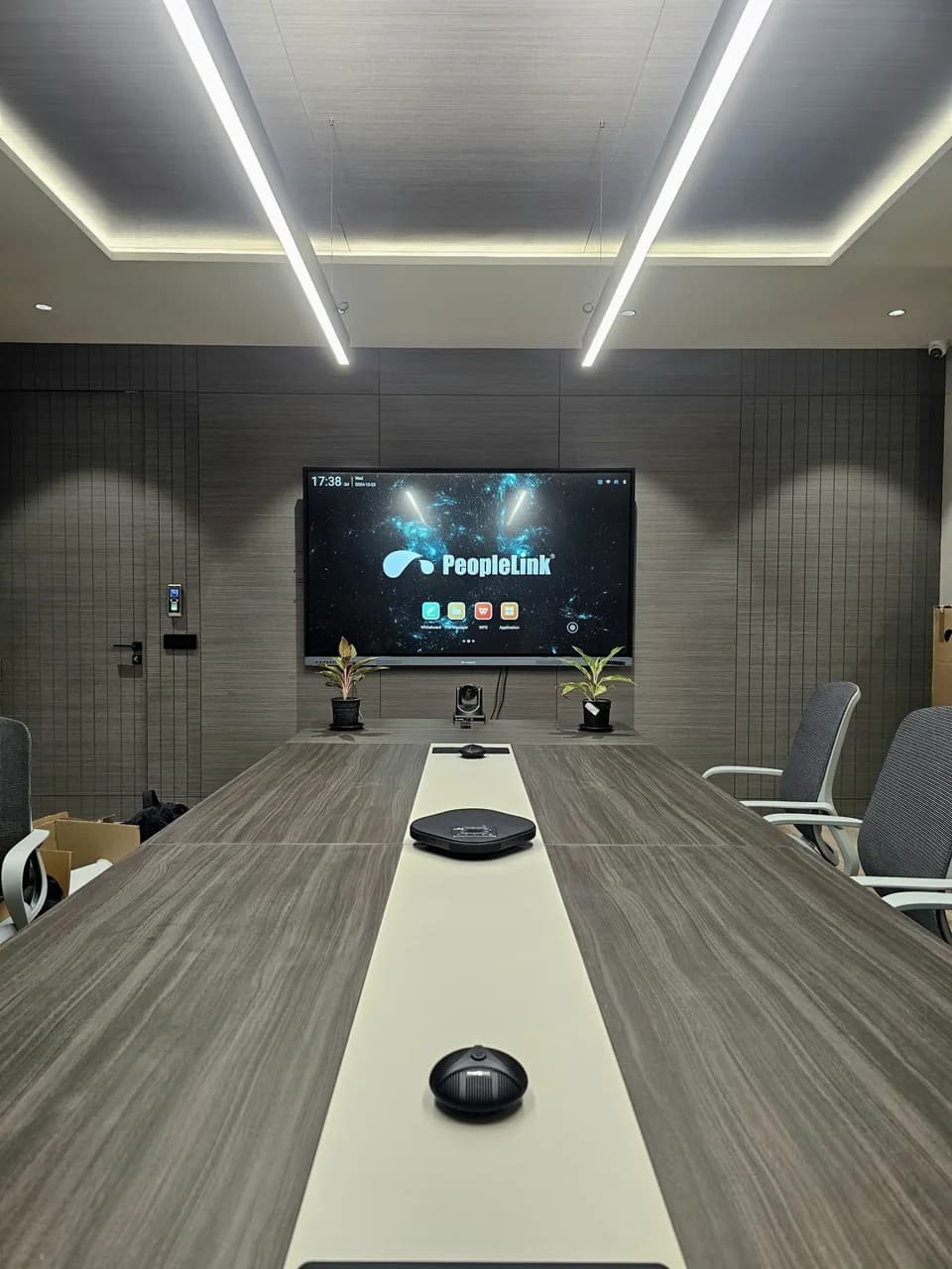 Cove-lit meeting room with interactive display and speakerphone on the table