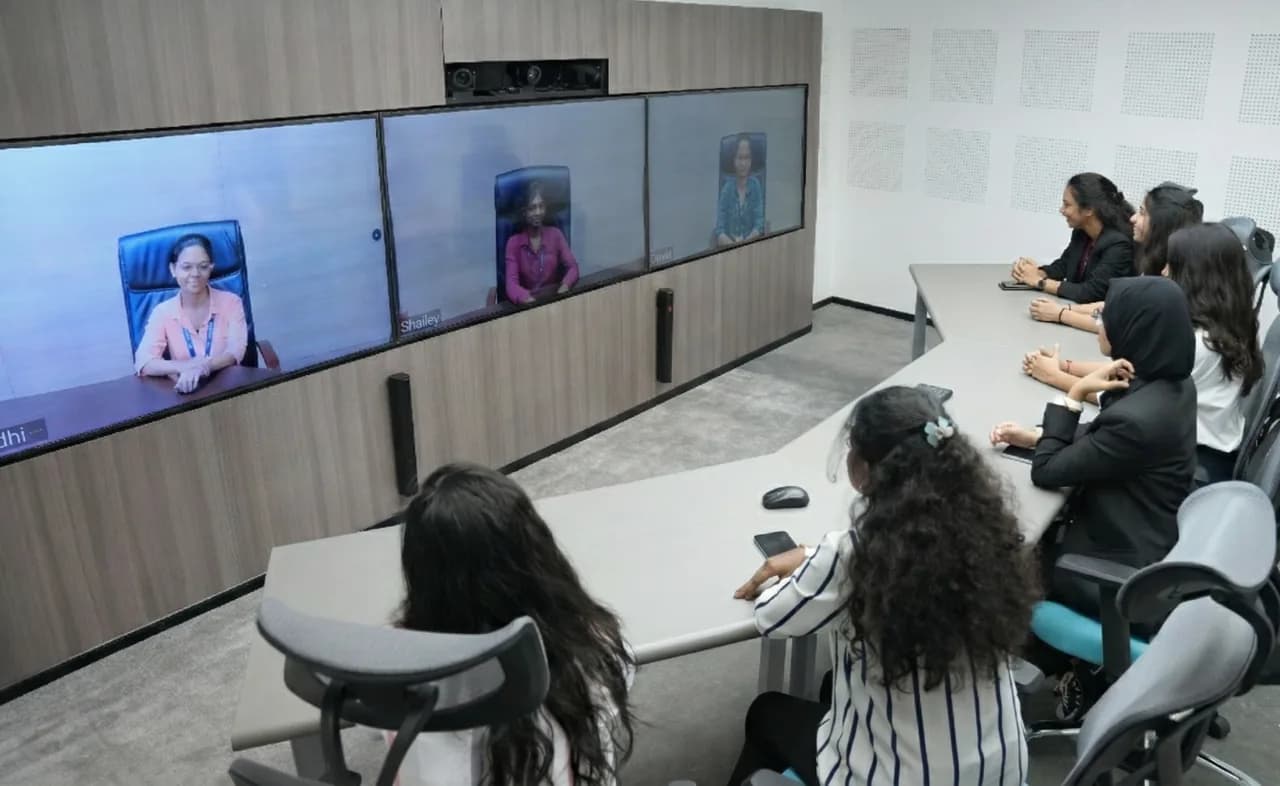 Students in a classroom on a live three-screen telepresence call